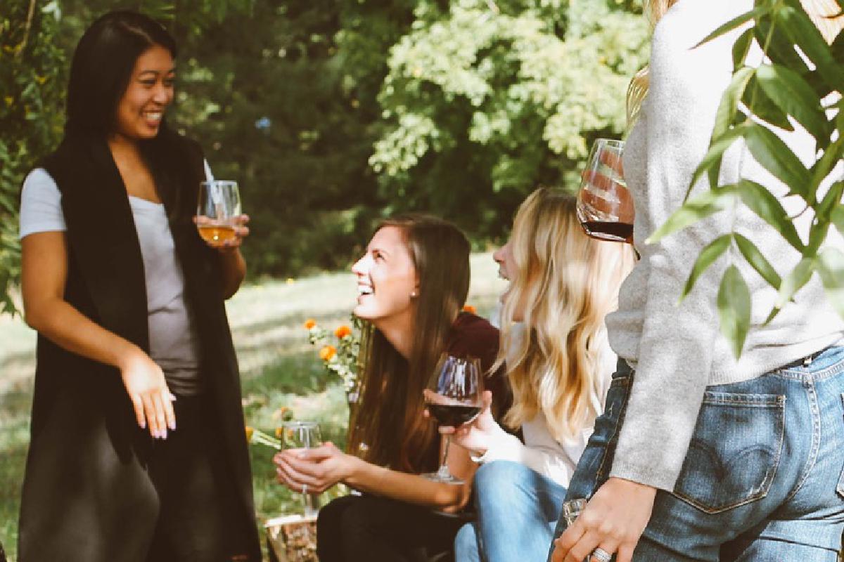 Lachende Frauen trinken draußen Wein