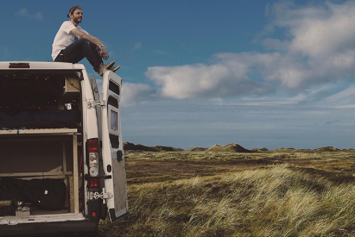 Künstler Mow Liebig sitzt auf seinem Van in der Natur