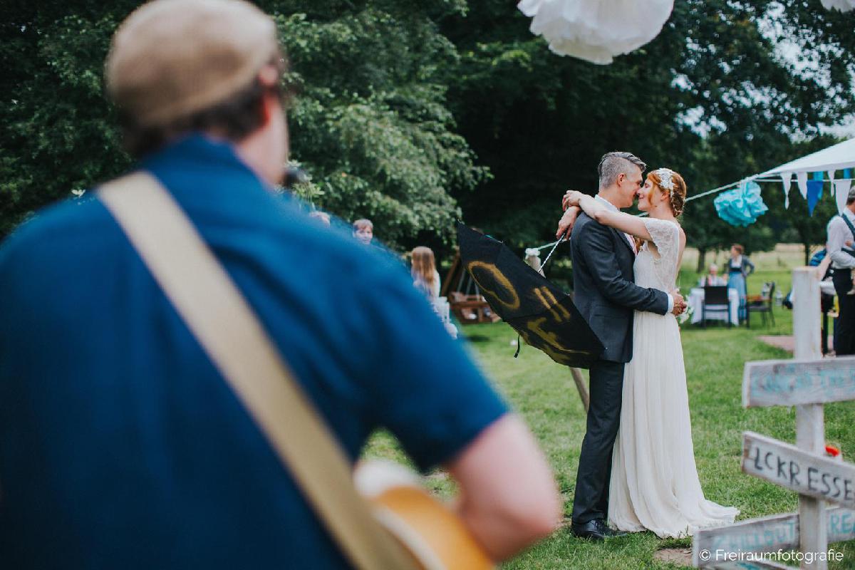 Ehepaar umarmt sich während Musiker Gitarre spielt