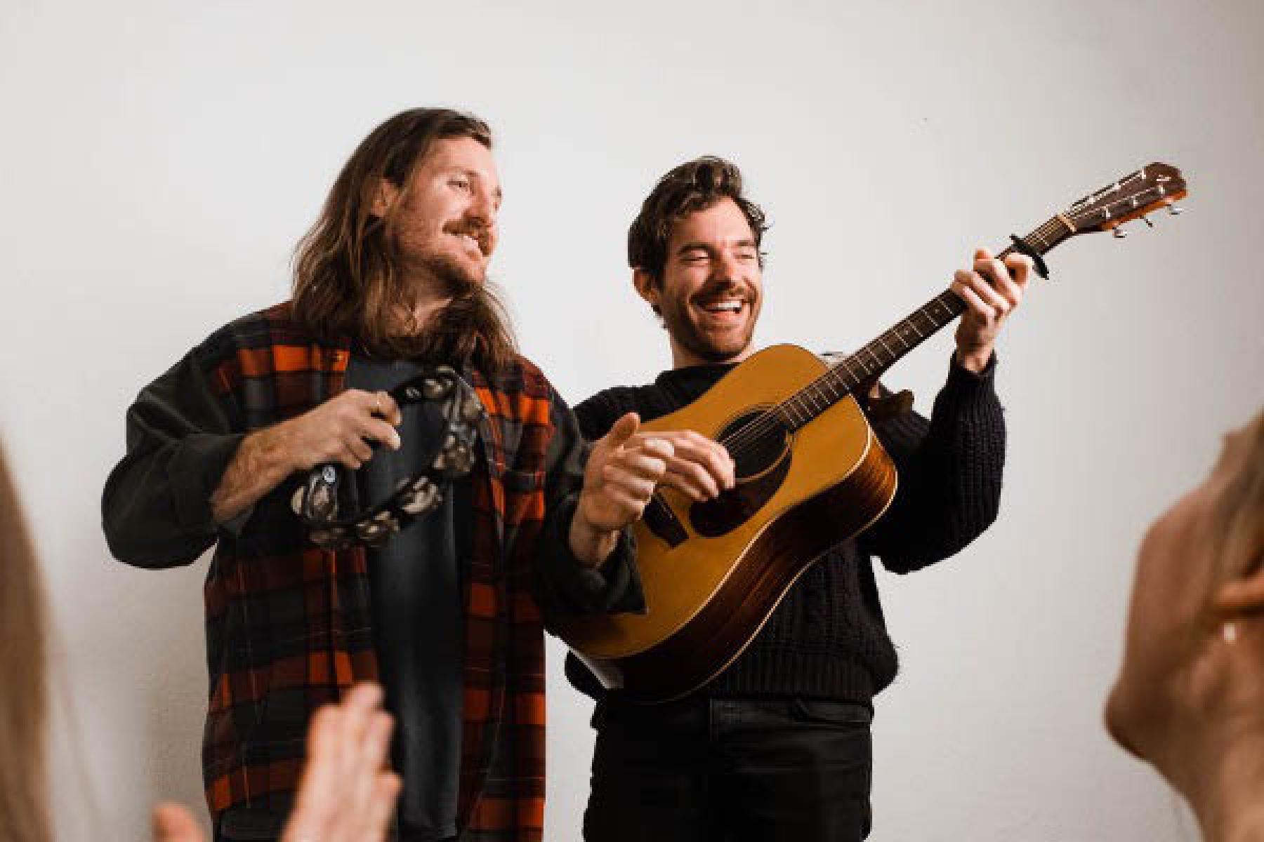 2 Künstler lachen und spielen Gitarre