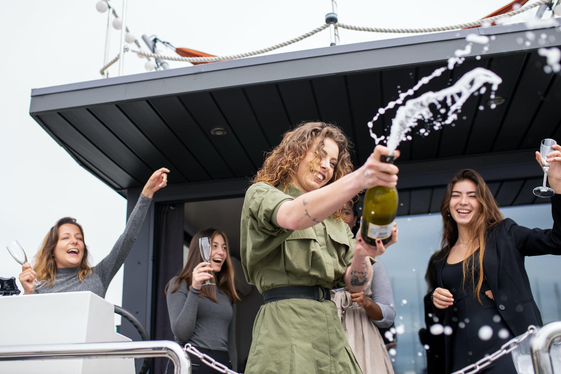 Fünf Frauen feiern mit Champagner auf einem Boot
