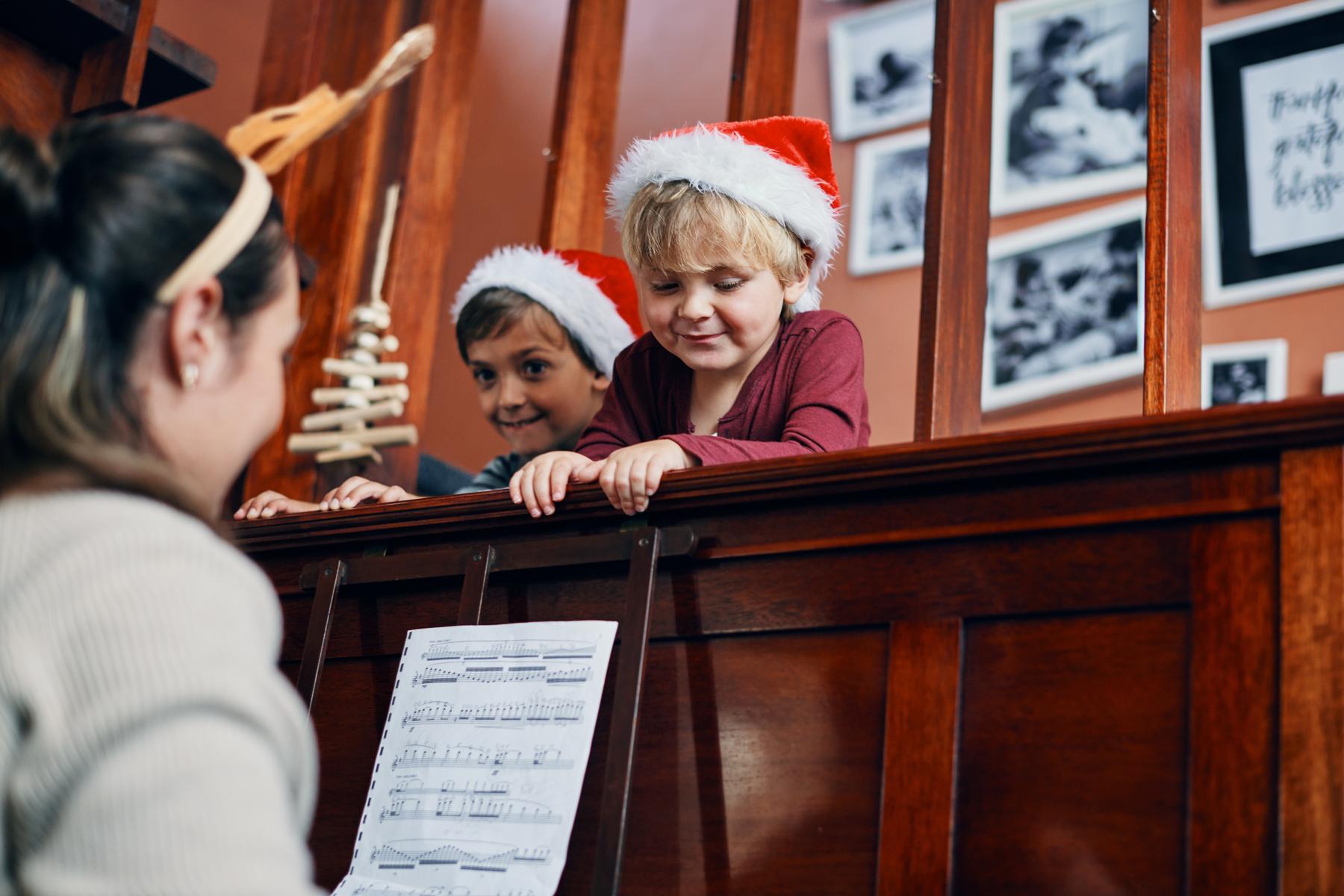 Young woman playing the piano for two little boys
